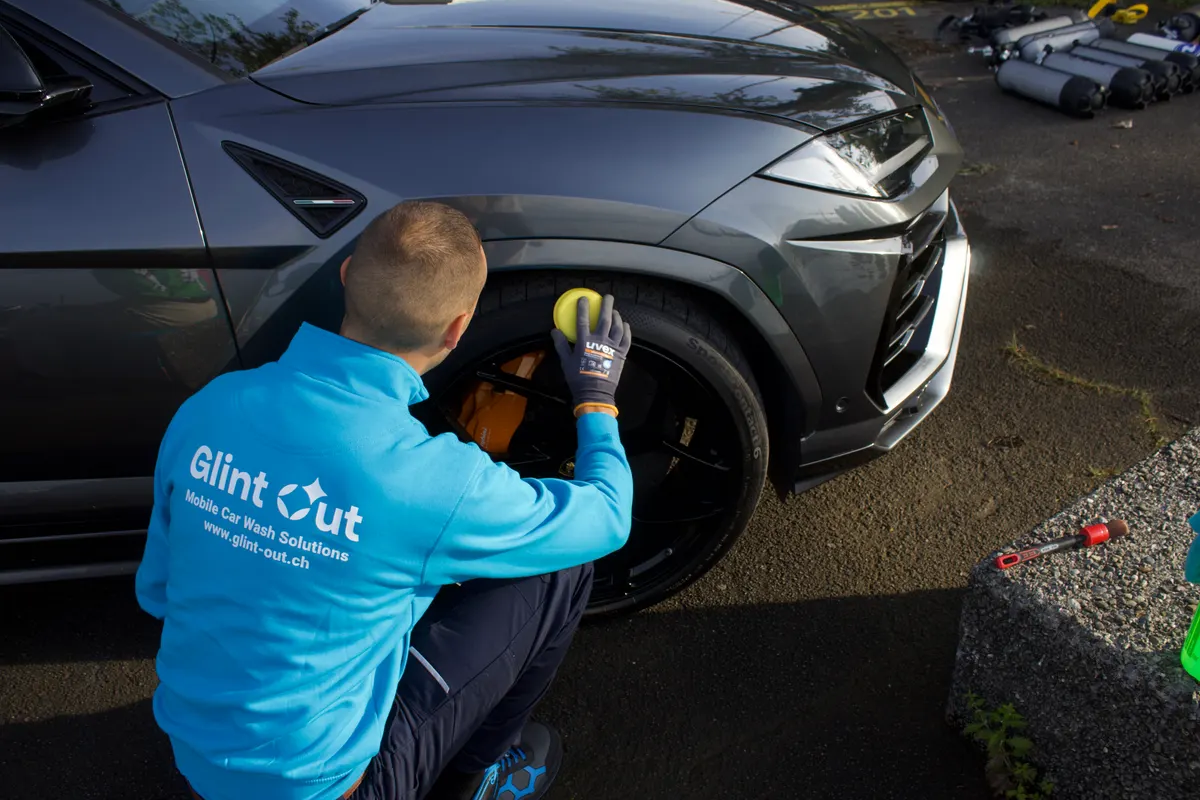 A Glint Out washer cleaning a car by hand with a cloth